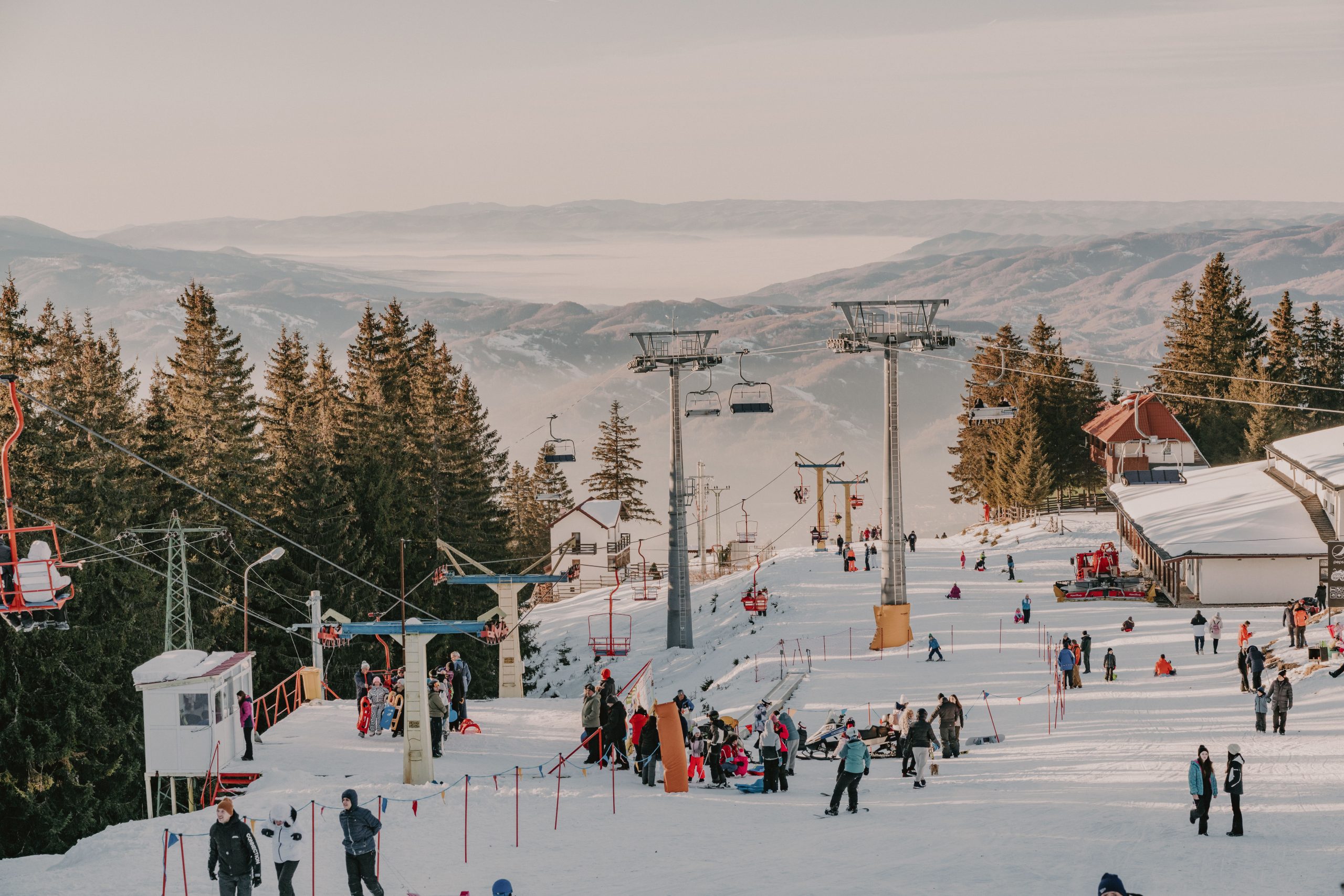 Winter activities at a ski resort in Romania's Parâng Mountains with snowy slopes.