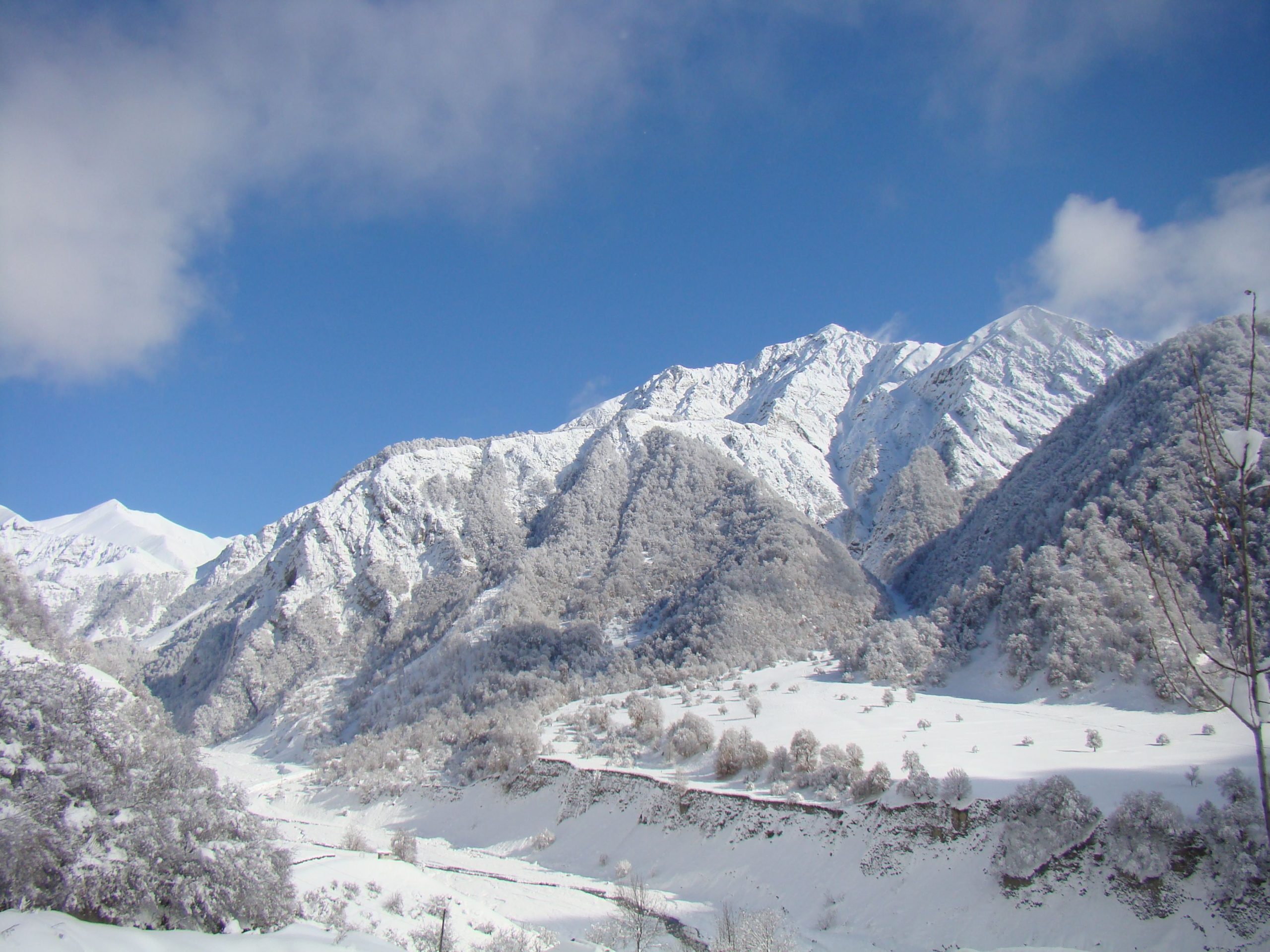 Stunning winter landscape of snow-covered mountains under a clear blue sky.